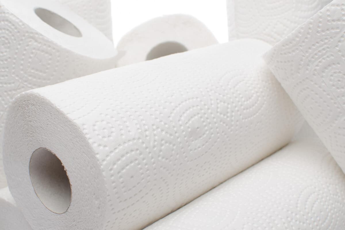 Several white paper towel rolls are stacked and arranged closely together.