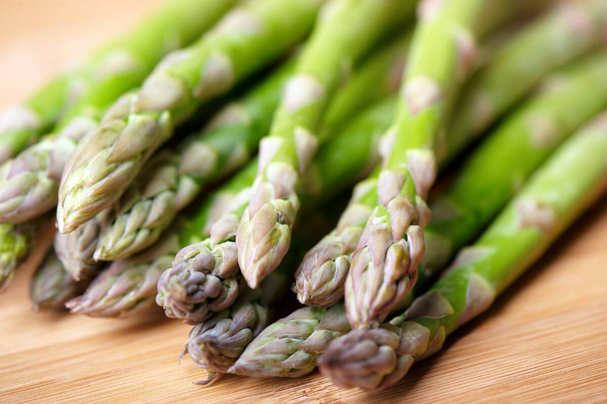 Close-up image of fresh, raw asparagus spears arranged on a wooden surface.