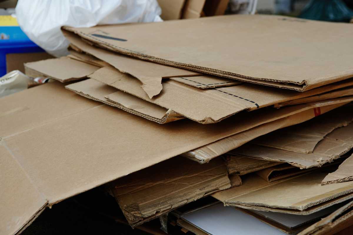 A stack of flattened cardboard boxes is piled together. Some of the pieces show minor tears and bends, indicating they have been previously used.