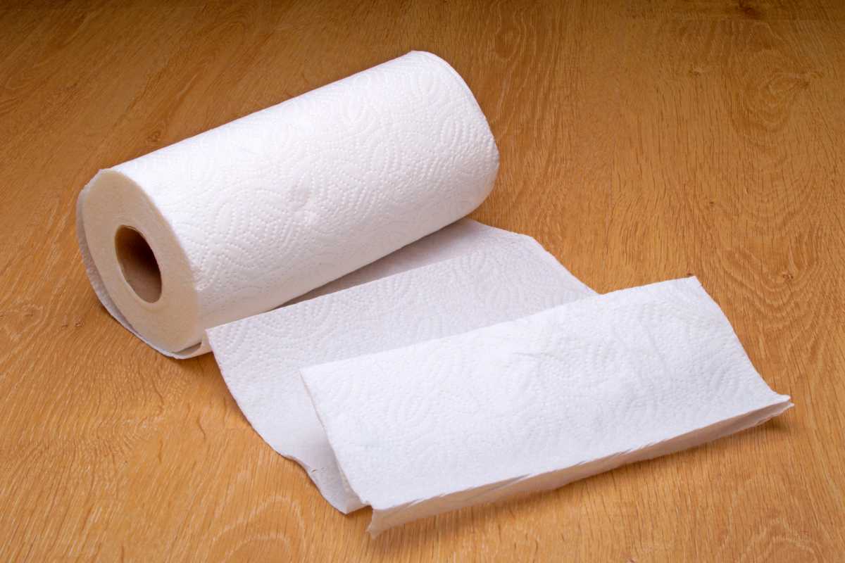 A roll of compost paper towels partially unrolled on a wooden surface. 