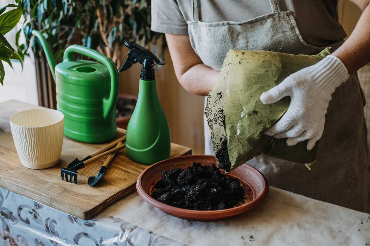 A person wearing white gloves is demonstrating how to make potting soil.