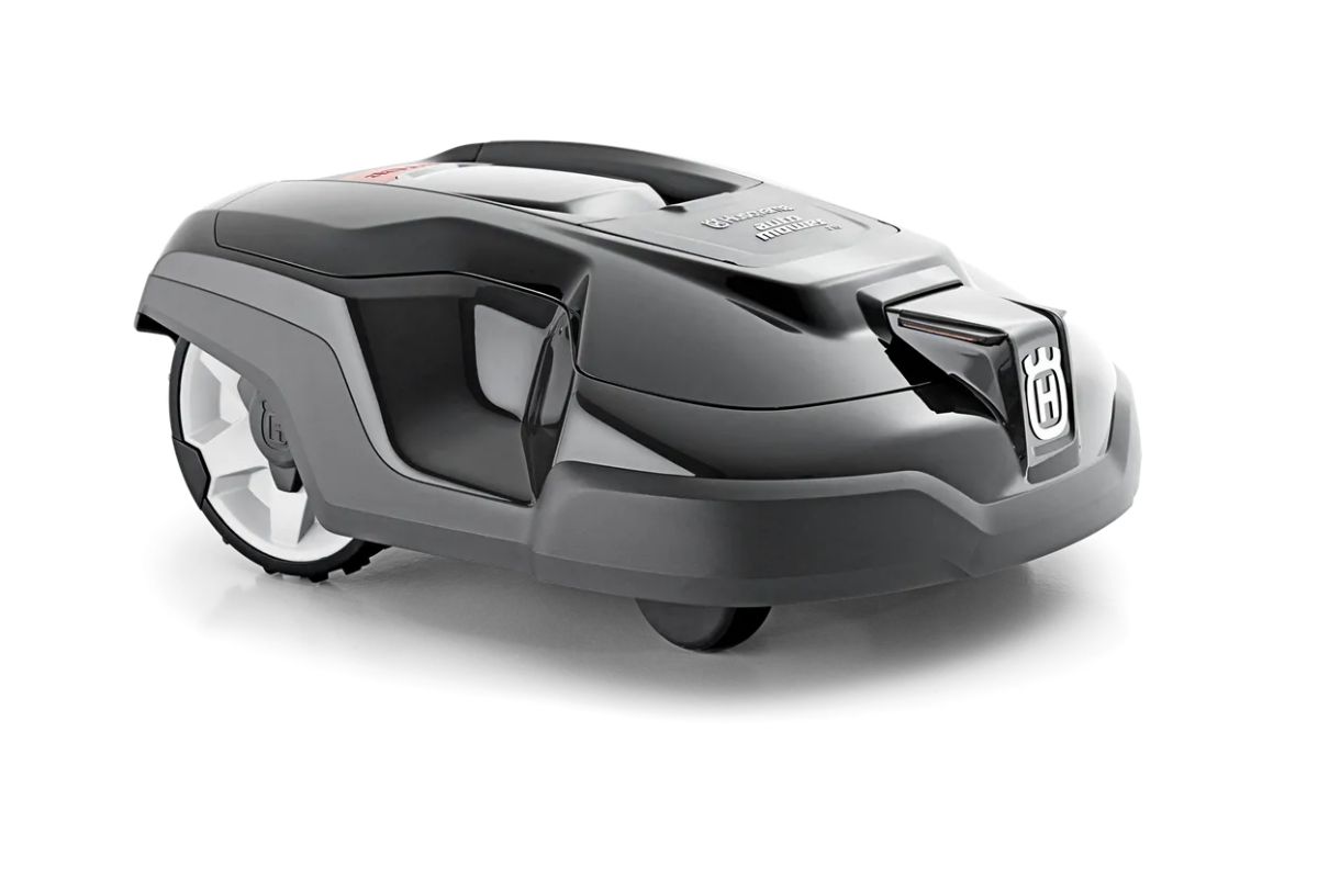 A sleek, modern robotic lawn mower in black and silver with a low-profile design, the Husqvarna Automower 310 features a compact body with two large wheels and two small wheels. The mower has a glossy finish and a brand logo on the front, all displayed on a white background.