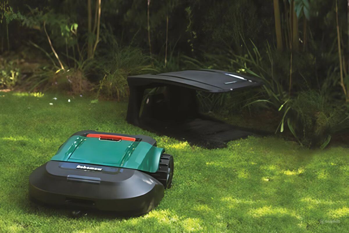 A Robomow RS630 with green and black casing rests on a green lawn near a black docking station.