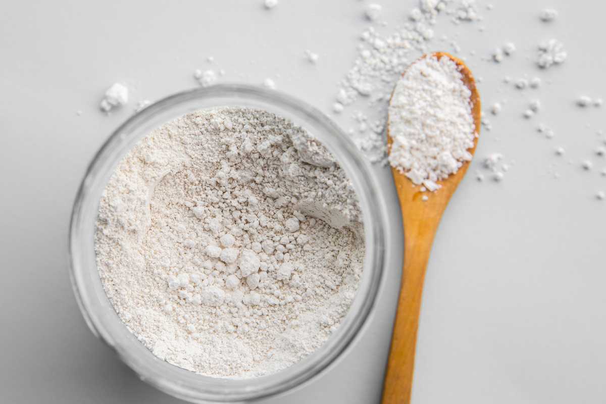 A glass jar filled with diatomaceous earth is placed on a light grey surface.