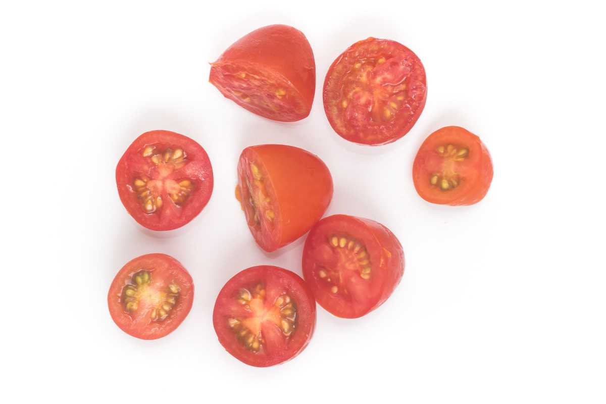 Overhead view of several cherry tomatoes sliced in half and arranged on a white background. 