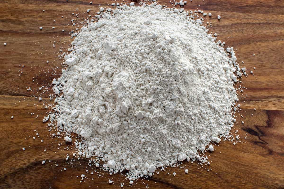 A large mound of Diatomaceous Earth is spread out on a wooden surface. 