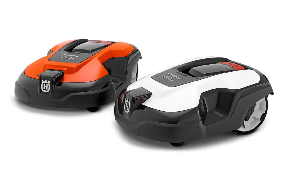 Two Husqvarna Automower 315 side by side: the left one is red and the right one is white. Both have sleek, modern designs with black accents and small wheels. 