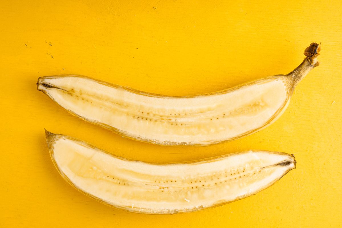 Two banana halves are placed parallel to each other on a vibrant yellow background. 