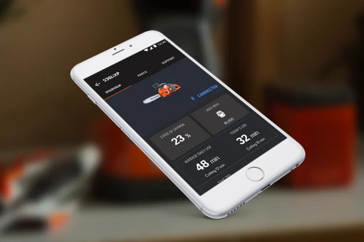 A white smartphone displays Husqvarna Connect@Home app interface for managing a Husqvarna Automower 310.