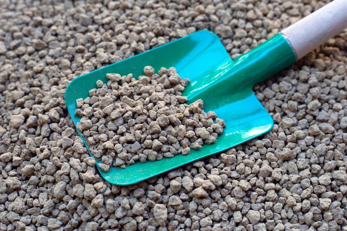 Akadama, an important component of bonsai soil mix, is shown being scooped by a gardening shovel.