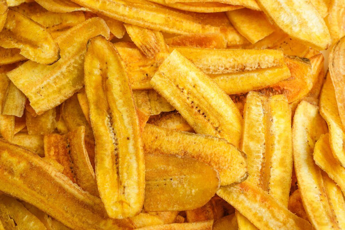 A close-up view of a pile of crispy plantain chips, showcasing their golden-yellow color and crunchy texture. 