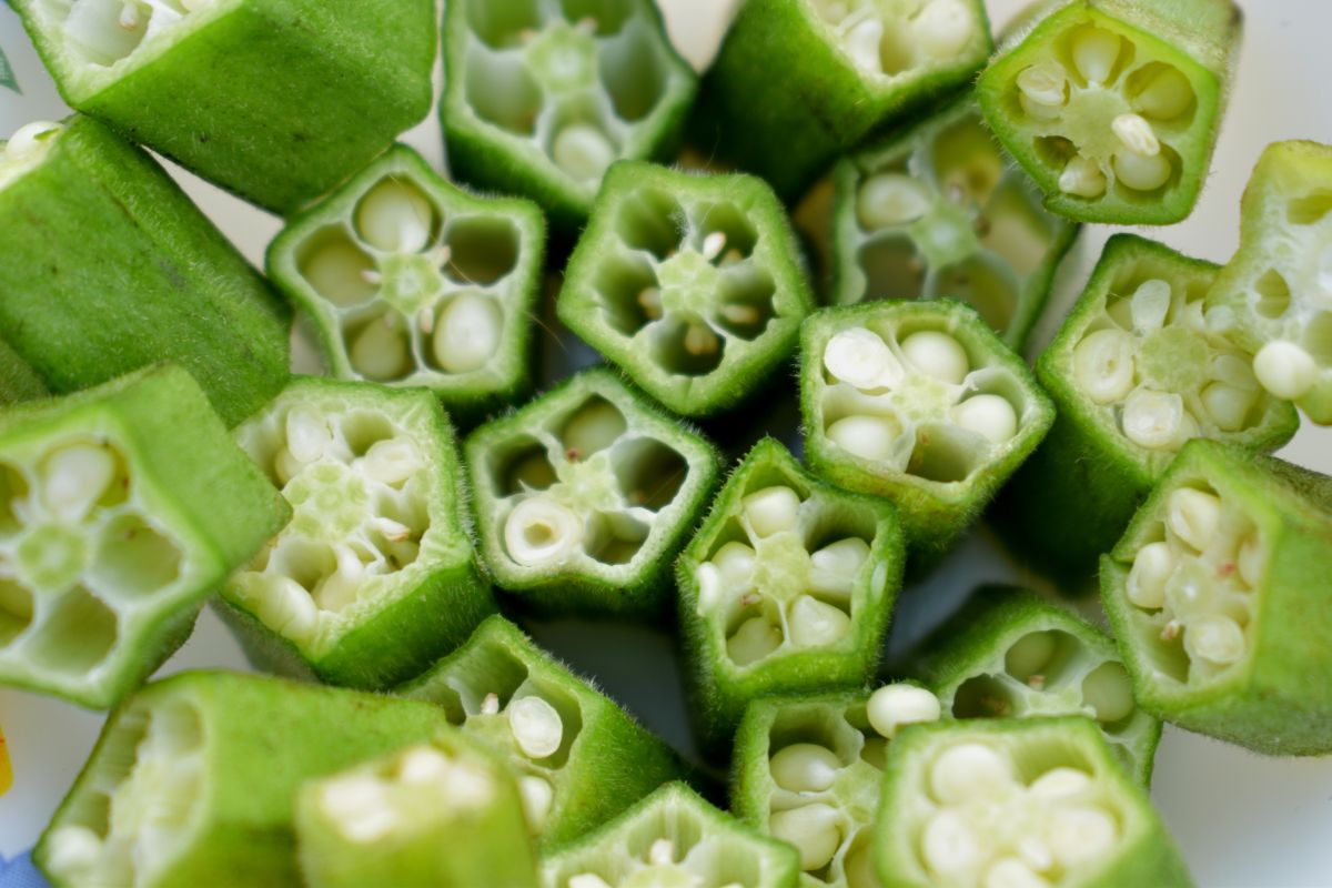 Several cut pieces of okra, showing the green pods and their interior white seeds. 