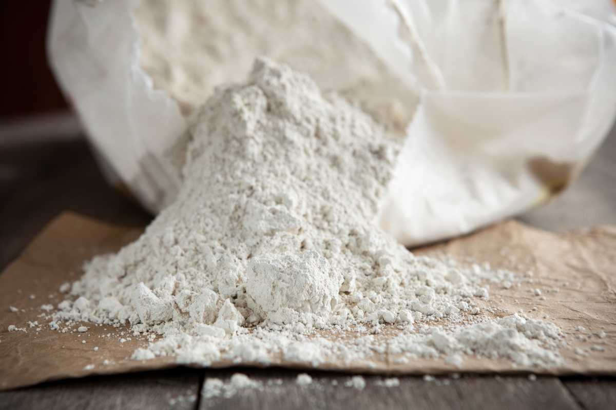 An open bag of diatomaceous earth spilling onto a brown paper surface. 