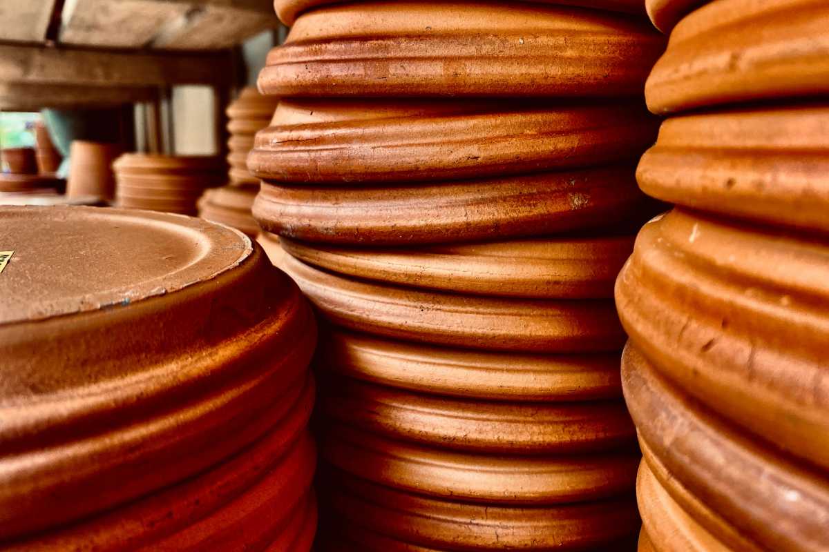 Multiple stacked terracotta pots in warm lighting. Each pot has visible ridges and a smooth, earthy texture. 