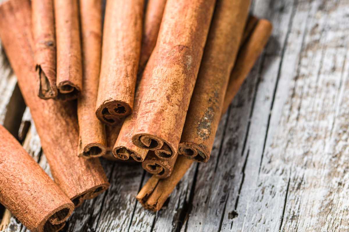 Several cinnamon sticks arranged haphazardly on a weathered wooden surface.