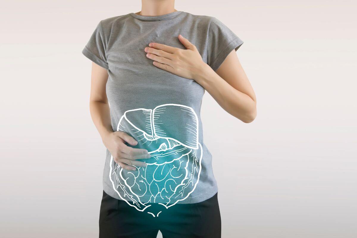 A person in a grey t-shirt holds one hand over their chest and the other over their lower abdomen.