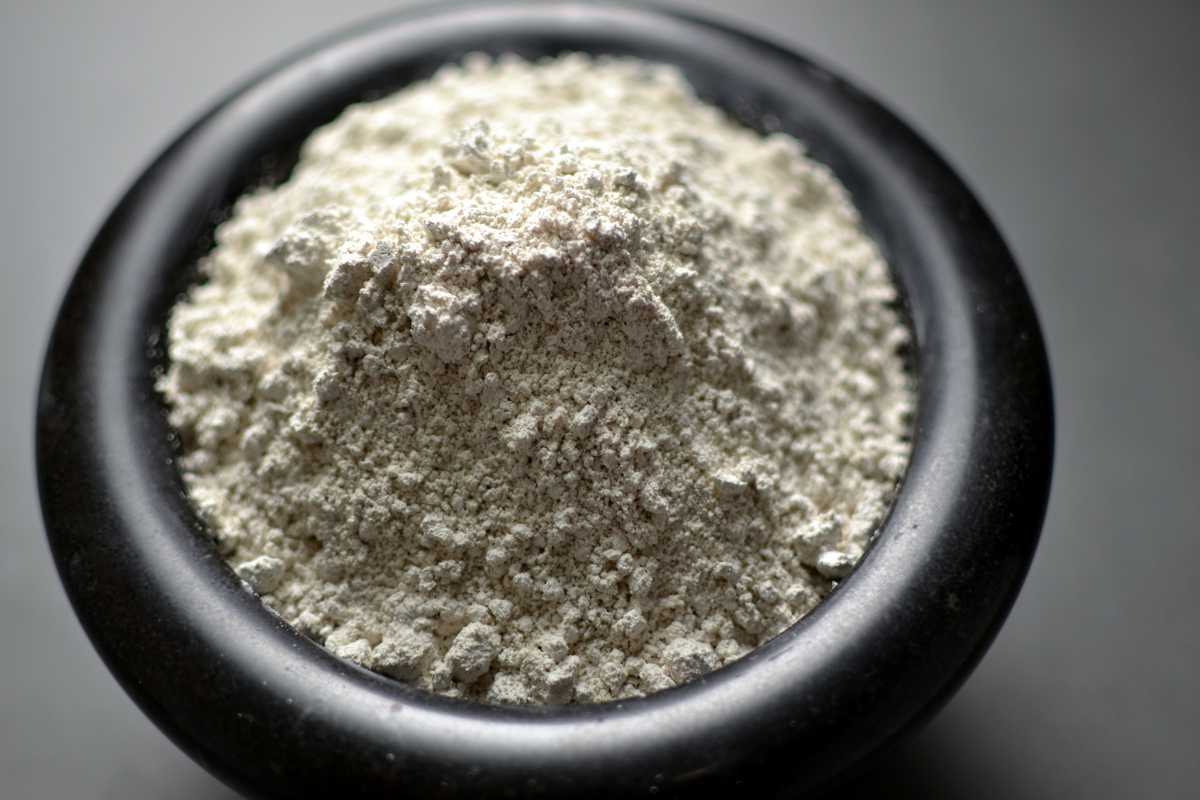 A black bowl filled with food grade diatomaceous earth on a dark surface.