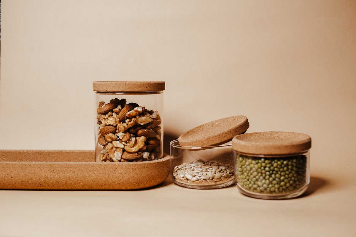 Glass containers with cork lids are filled with various seeds.