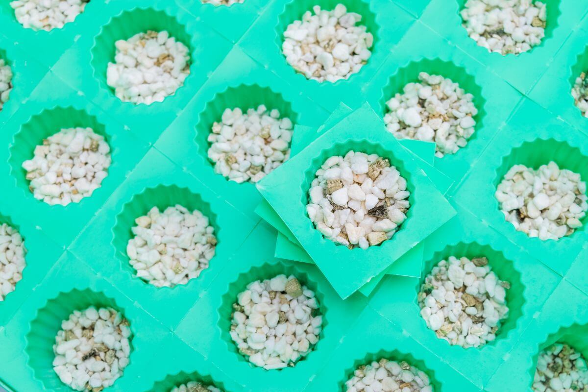 A close-up of multiple green hexagonal containers filled with small white hydroponic vermiculite and perlite.