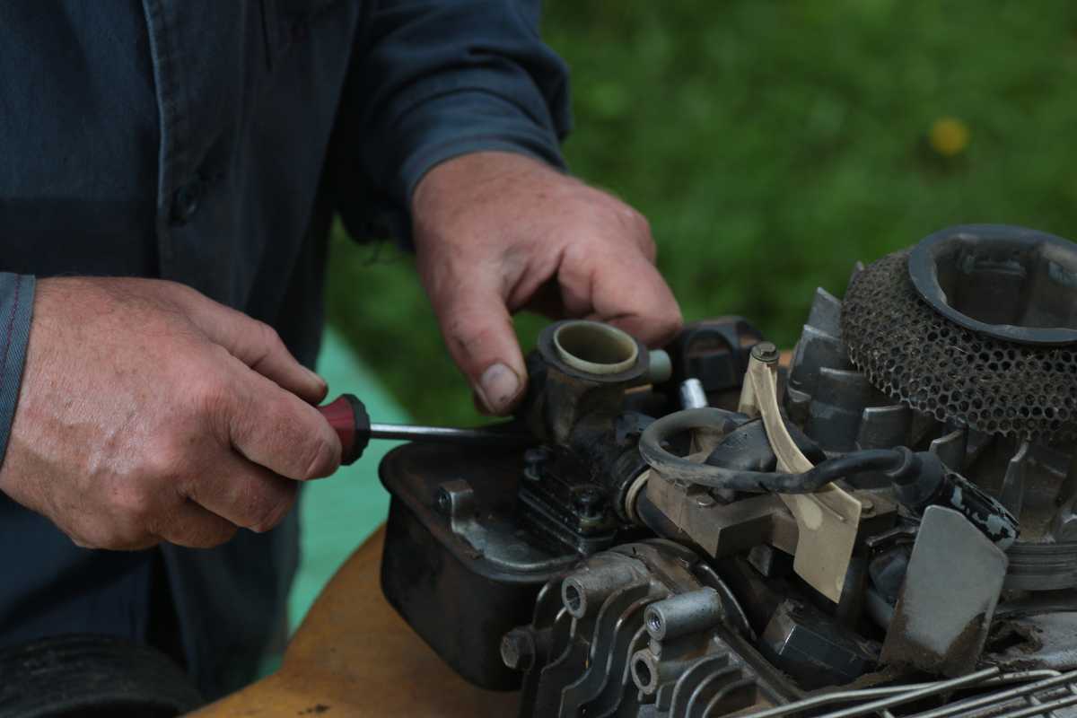 A person using a screwdriver to work on an engine of a robot mower.