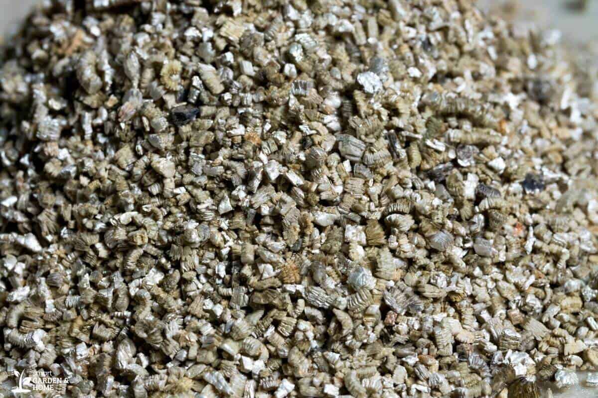 A close-up photo of a pile of brown and tan coarse vermiculite particles.