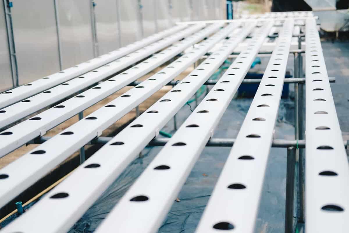 A close-up view of an empty hydroponic growing system with multiple white plastic channels, set up in an indoor facility.