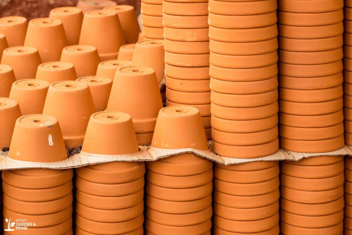 A large stack of terracotta pots seen from the side, with some pots facing downwards and others stacked inside each other.